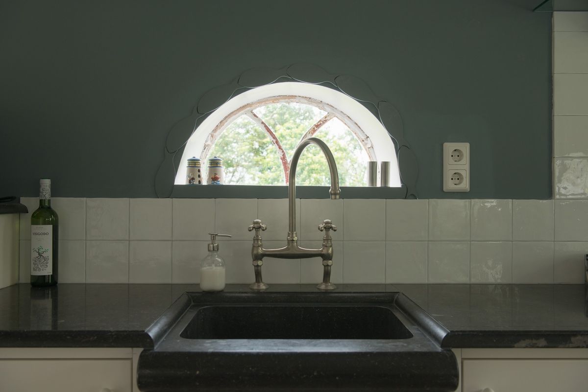 Keuken met zwart spoelbak, vintage mengkraan en boogvenster – Zeeuwshuisje vakantiewoning, Koudekerke