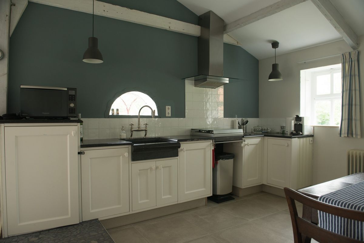 Volledige keuken met witte kasten, roestvrijstalen afzuigkap en blauwe muren – Zeeuwshuisje vakantiewoning, Koudekerke