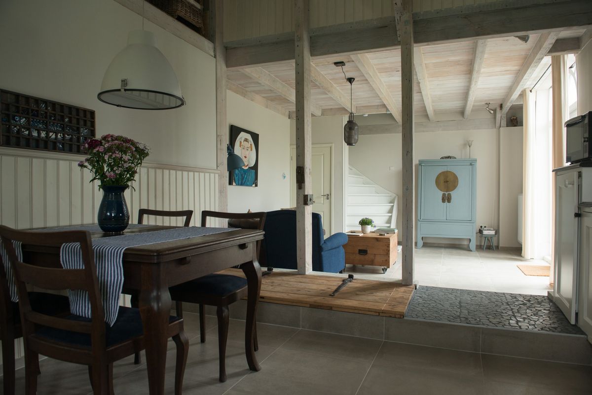 Open woon- en eetgedeelte met trap en vintage blauwe kast – Zeeuwshuisje vakantiewoning, Koudekerke