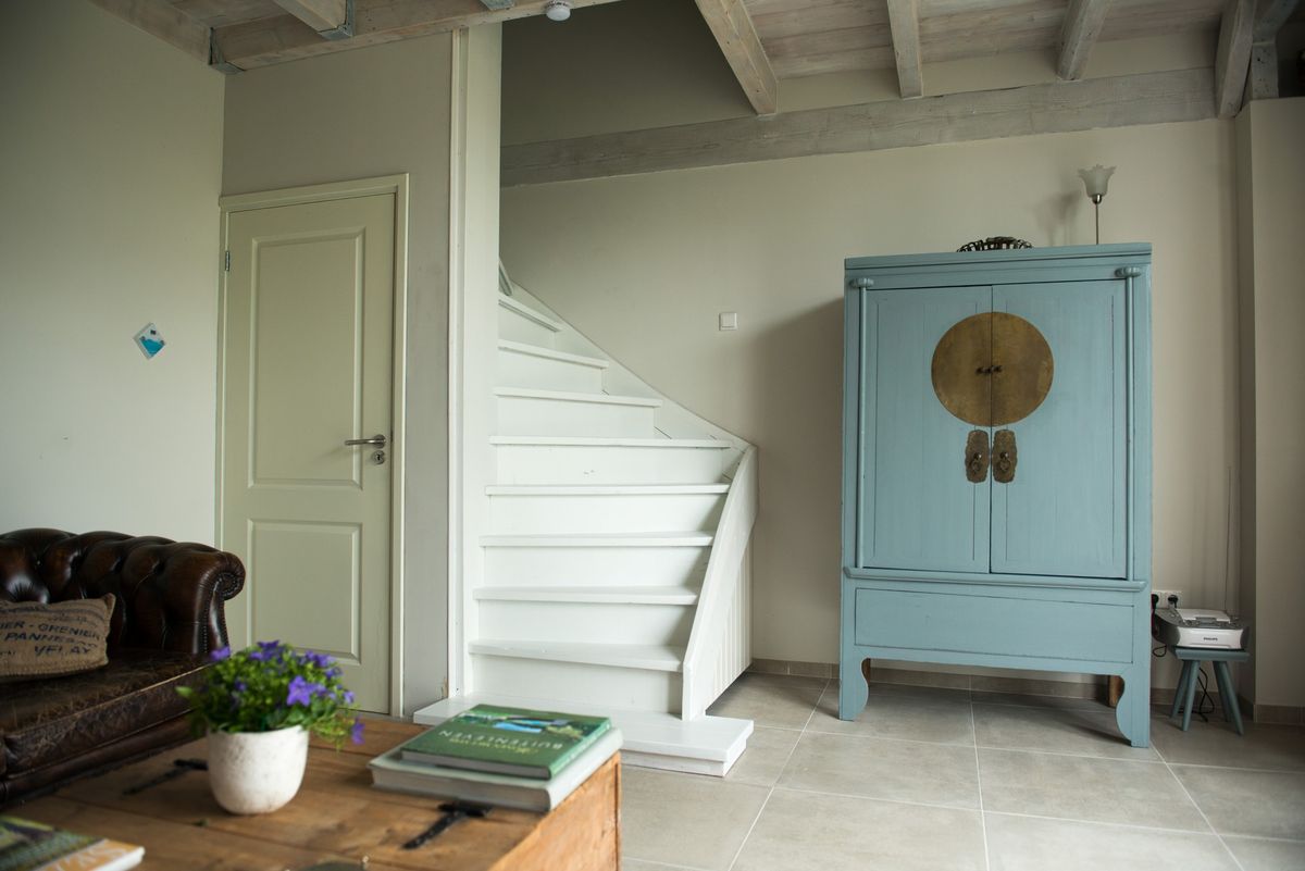 Witte trap naar de eerste verdieping met blauwe Oosterse kast – Zeeuwshuisje vakantiewoning, Koudekerke