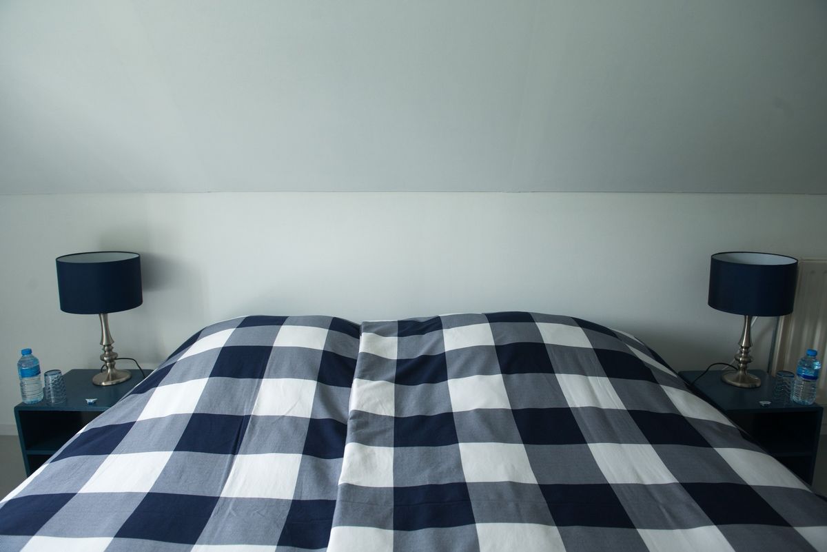 Tweepersoonsbed in hoofdslaapkamer met marineblauw geruite dekbedovertrek – Zeeuwshuisje vakantiewoning, Koudekerke