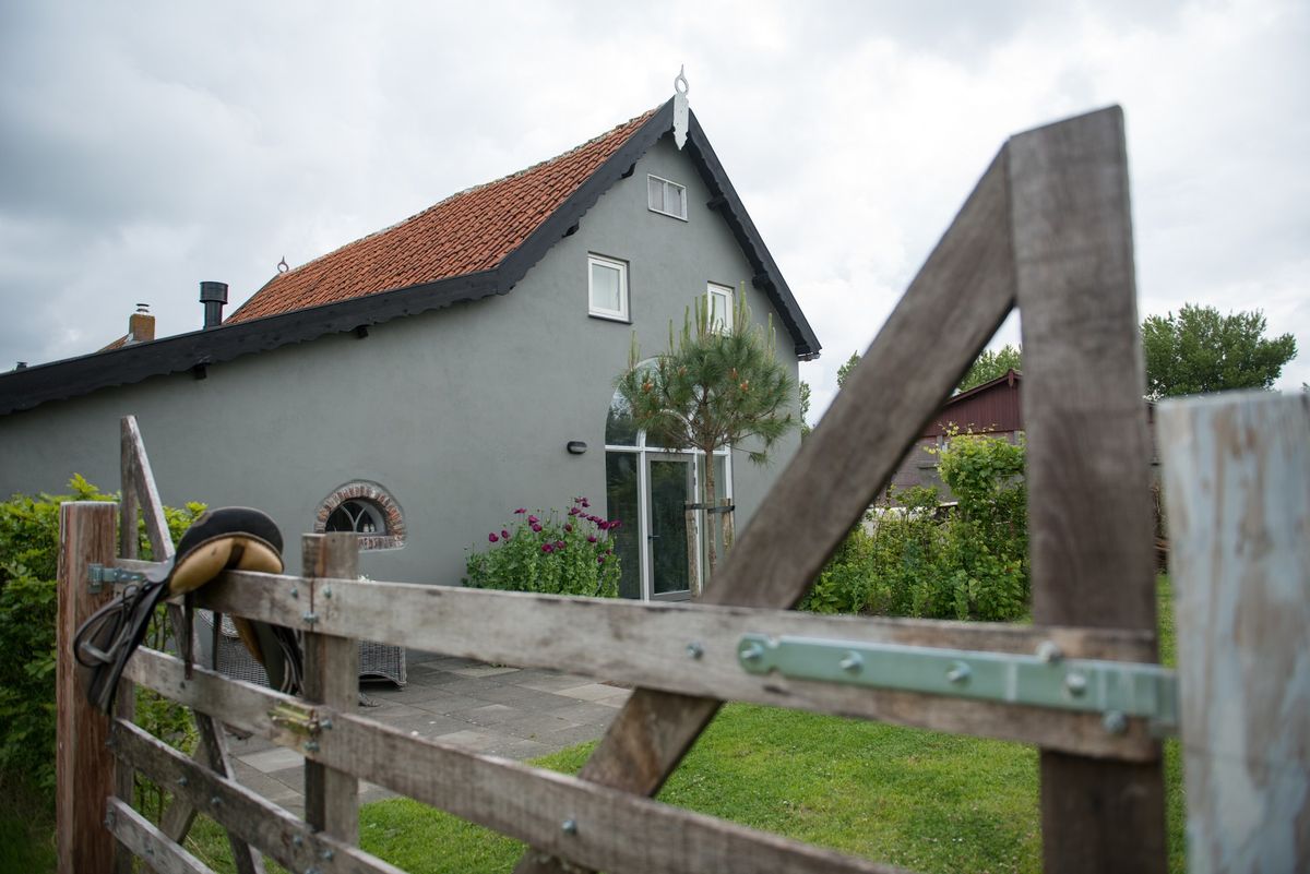 Exterieur van de boerenstal gezien door rustiek houten hek – Zeeuwshuisje vakantiewoning, Koudekerke